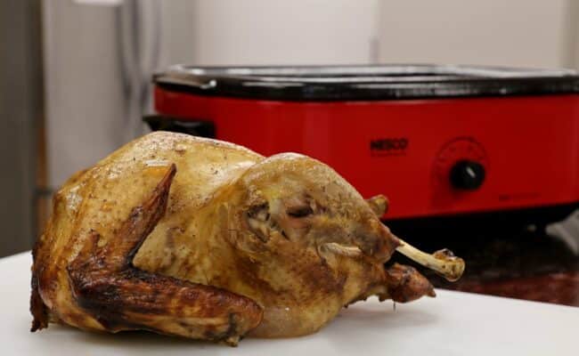 Roasted Turkey In Front Of Red NESCO Roaster Oven